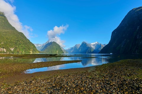 Natural wonder with reflections in a body of water in front of forested mountains, summer, Milford
