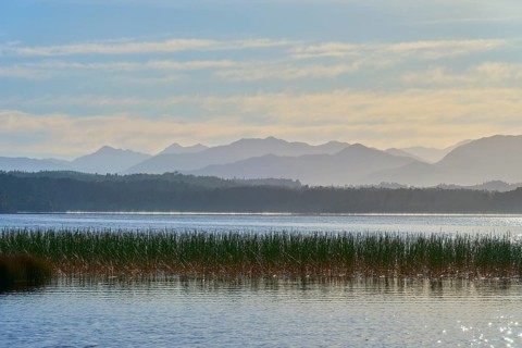 Lake against a mountainous backdrop and cloudy sky, Lake Mahinapua, Ruatapu, South Island, New