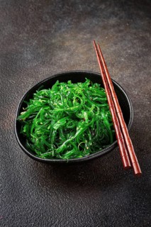 Chuka salad, made from fresh seaweed, with sesame dressing, served in a black bowl, with chopsticks