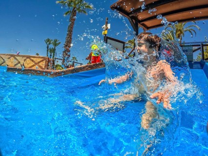 Young boy enjoying summer vacation splashing in a swimming pool at a water park, creating a