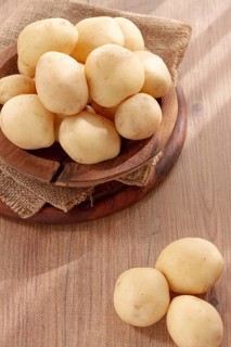 Boiled new potatoes, in a wooden bowl, on a rustic table, natural light, no people