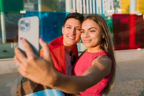 A smiling lesbian couple takes a selfie together, celebrating love and LGBTQIA+ pride. One partner