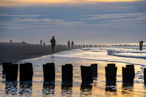 Winter on the North Sea, sunset at the beach, joggers, beach walkers, coastal protection, through