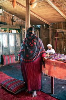 Bedouin woman, 60 years old, wearing a face mask in a Bedouin house made of palm fronds, Wahiba