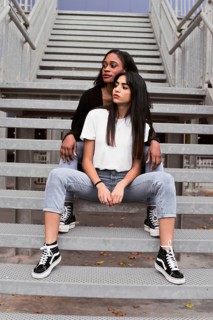 Two friends exude confidence and style while sitting on metal stairs in an urban setting. Their