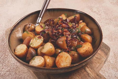 Crispy roasted potatoes with saut?ed onions and herbs served in a rustic bowl