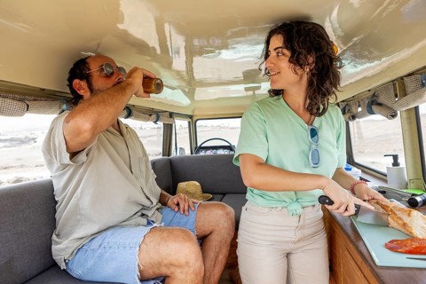 A blind man and a woman in a motorhome, enjoying a relaxing moment. He is sipping a drink while she