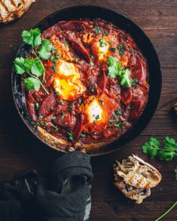 Savor the vibrant colors and enticing aroma of a traditional shakshuka dish with poached eggs in