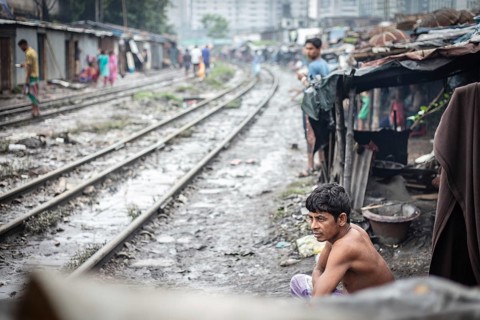 Residents sit by the railway tracks in the Tejgaon slum area, Dhaka, Bangladesh