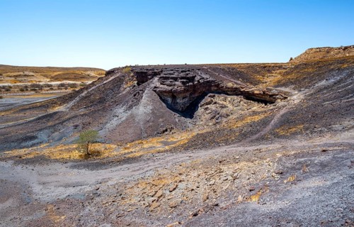 Dry landscape with yellow grass and black volcanic hills, Burnt Mountain, Damaraland, Kunene,