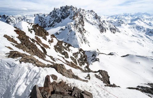 Mountaineer climbing up a steep snow slope, secured by a rope, ascent to the summit of Piz