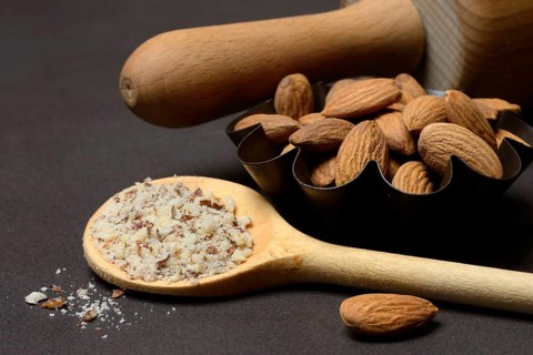 Almonds and ground almonds in cooking spoon, Prunus amygdalus