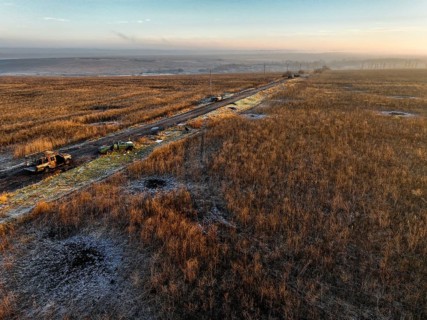 From above, image of military vehicles parked along a rural road impacted by the war through a