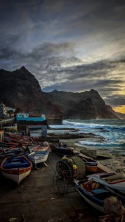 Colourful boats along a rocky seashore with dramatic skies, romantic harbor scene in the evening
