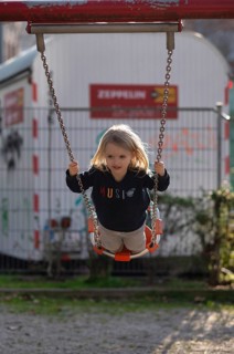 Girl, 4 years, blonde, swinging on swing, public playground, urban, Stuttgart, Baden-Württemberg,