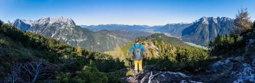 Mountaineer on a hiking trail between mountain pines, autumnal mountain landscape, ascent to the
