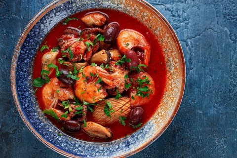 Seafood in tomato sauce with olives, on a dark blue background