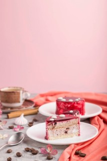 Red cake with souffle cream with cup of coffee on a gray and pink background and red textile. side