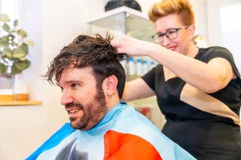 Close-up of friendly and cool hairdresser attaching a clean capillary prosthesis to a man