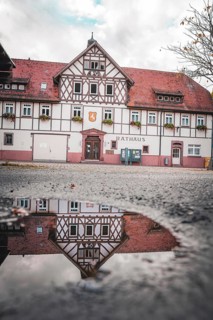 Historic town hall with reflection in puddle, Hirsau, Calw, Black Forest, Germany