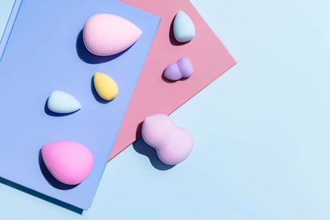 Top view of an array of multicolored makeup sponges, each uniquely shaped for beauty application,