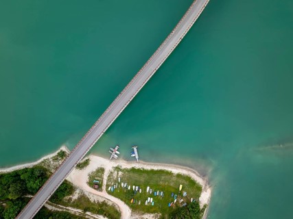 Top-down drone image of Castreccioni Lake showing a bridge crossing turquoise water and a small