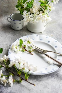 Elegant white floral table setting showcasing delicate blossoms on a ceramic plate with cutlery. A