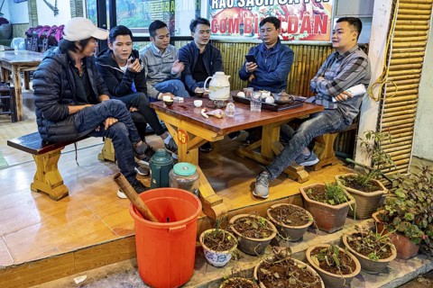 A group of men sit in a cosy café, drinking tea and chatting, restaurant in the streets of Sa Pa in