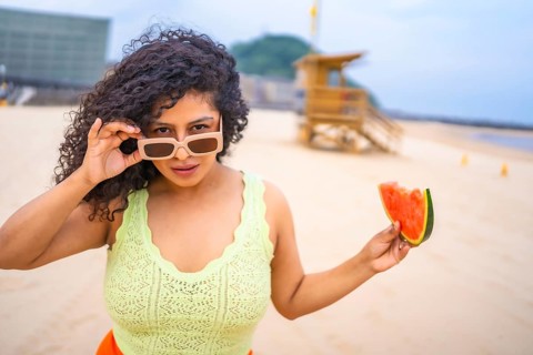 Portrait of Latin woman in summer on the beach on vacation with hat and a watermelon