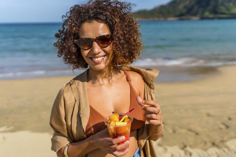 Arab female modern traveler eating tropical fruit on a sandy beach