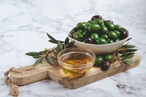Chalkidiki olives, classic Greek green olives, in a bowl on a cutting board, top view, without