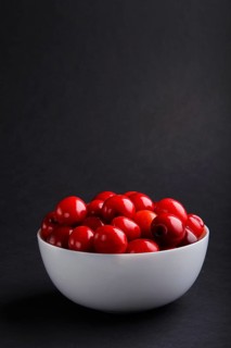 Fresh red sweet cherry in white bowl on black background. side view, copy space