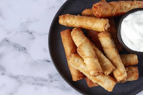 Fried spring rolls with cheese, on a plate, with cream sauce, no people