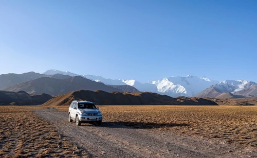 Off-road vehicle in front of snow-covered mountains, Pamir Mountains with Lenin Peak, high