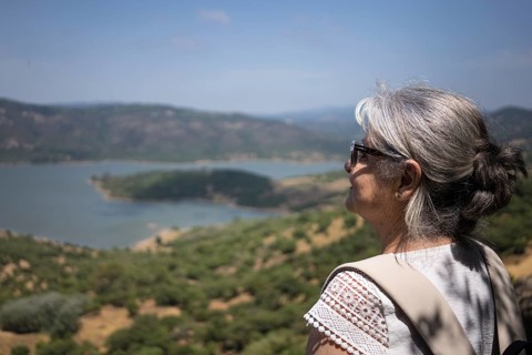 An older woman with gray hair gazes over the scenic landscape of Castellar de la Frontera in Cadiz,