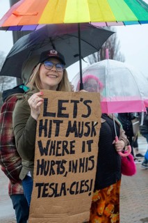 Troy, Michigan USA - 29 March 2025 - People gathered in the rain outside the Tesla Showroom at the