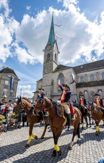 Historically costumed guild members in Zurich's old town, riders in front of the Fraumünster