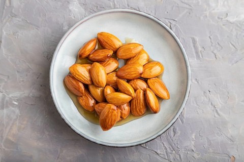 Almonds with honey on gray concrete background. top view, flat lay, close up