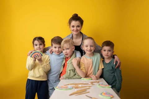 A group of children and their teacher engage in a fun and creative lesson with colorful crafts on a