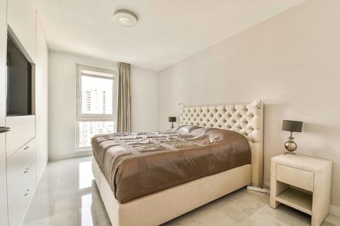 Modern minimalist bedroom showcasing a plush bed, elegant bedside lamps, and soft beige tones.