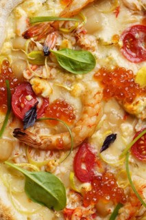 Close up view of a delectable gourmet pizza topped with succulent shrimp, vibrant red caviar,