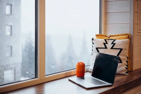 A peaceful remote work environment featuring a laptop and an orange thermos cup beside a