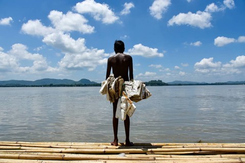 A boy wearing polystyrene sheets ready to dive in the Brahmaputra river during a hot summer day, in