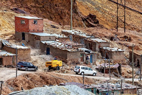 Quiet mining settlement with huts and parked vehicles surrounded by desert landscape, The silver