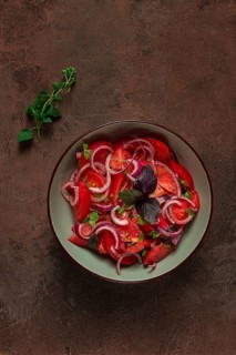 Fresh tomato salad, with red onion, spices and herbs, top view, close-up, homemade
