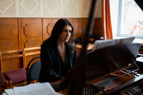 A female musician passionately plays the piano with a focused expression in a cozy room Soft