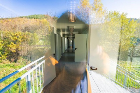 Reflection in the window shows the interior of the building and the outside natural environment,