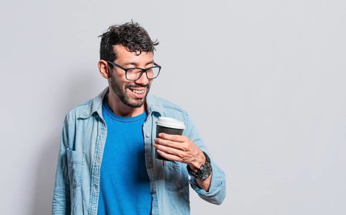 Excited person holding coffee glass on isolated background, Excited young man holding paper coffee
