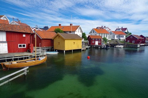 Colourful wooden houses on the coast, with boats and under a clear sky, idyll, crystal clear water,