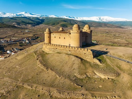 The Renaissance castle of La Calahorra against the snow-capped Sierra Nevada mountain range, aerial